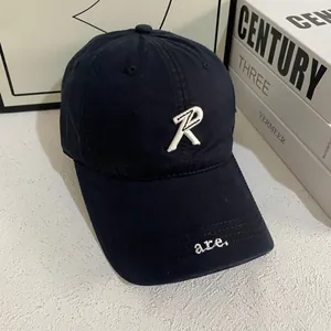 Detailopname van de donkerblauwe baseballpet met wit R-borduursel en brede klep
