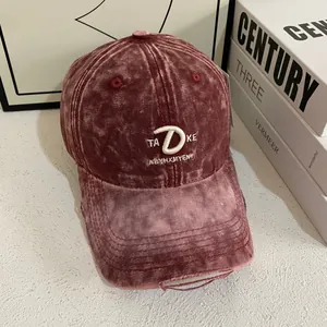 Detail of vintage washed burgundy baseball cap with 3D letter embroidery and distressed brim