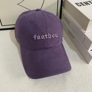 Detail view of purple washed cotton baseball cap with embroidered lettering and stitching