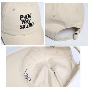 Vista detallada de gorra de algodón beige con texto bordado y hebilla de metal
