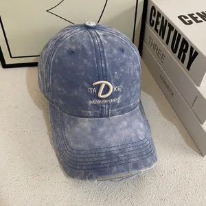 Close-up of distressed washed blue denim baseball cap with vintage embroidery and worn edges