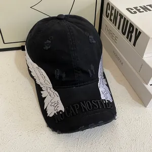 Detail of embroidered angel wings and NO CAP NO STYLE text on distressed black baseball cap