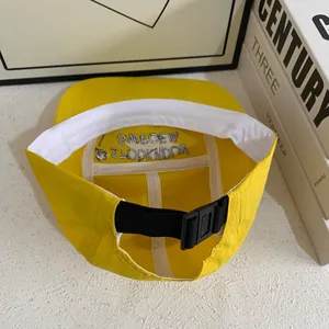 Detail view of yellow nylon camper hat featuring inner brand embroidery and buckle strap