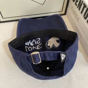 Detalle de gorra de béisbol azul marino con bordado PARIS LOVE blanco y hebilla de metal