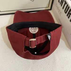 Dettaglio dell'interno del cappello bordeaux con fibbia in metallo e logo interno