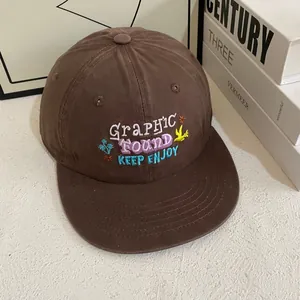 Detail of embroidered floral patterns and typography on a brown snapback baseball cap