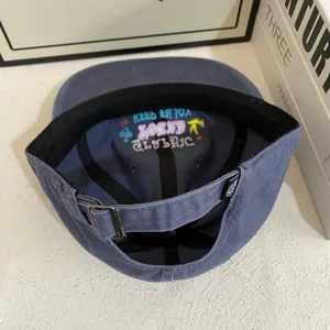 Detail of navy baseball cap interior with colorful embroidery and metal buckle strap