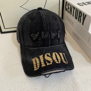 Detail of washed black baseball cap with YUPI embroidery and yellow DISQU graffiti brim