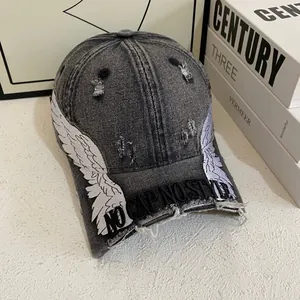 Detailed embroidery of white wings and distressed denim texture on a baseball cap