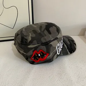 Detail of camouflage military cap with red lips embroidery and white GIG lettering