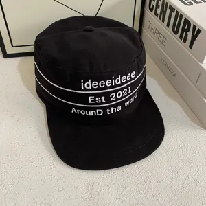 Close-up of black flat top military cap with white Est 2021 embroidery and stitching