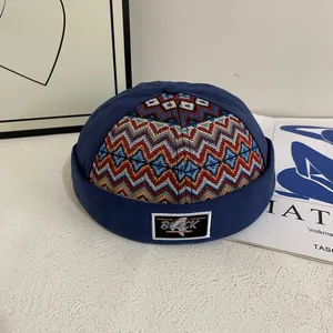 Navy blue docker hat with colorful wave embroidery and black woven patch on studio table