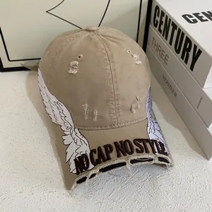 Close-up of distressed khaki baseball cap with wing embroidery and 3D textured lettering