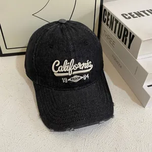 Retro distressed black denim baseball cap with California embroidery on white table