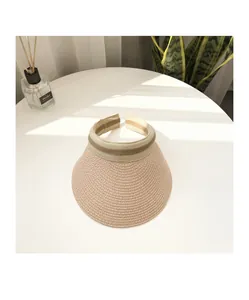 Detail of the pink straw-woven sun visor with striped ribbon trim on a white table
