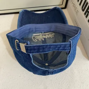 Detail view of the metal adjustable buckle and California embroidery on denim baseball cap