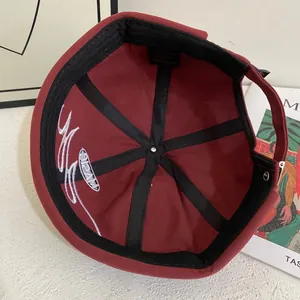Detalle del gorro docker burdeos con etiqueta 100% algodón y refuerzo interior