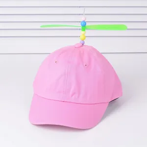 Pink kids baseball cap with colorful beads and a green propeller toy on top