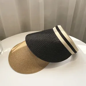 Straw sun visor hat with wide brim in black and natural beige on white table