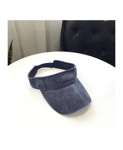 Detail view of the gray-blue washed denim visor with adjustable strap on a white table