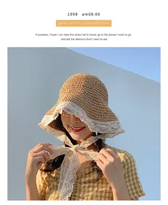 Detail of woven straw sun hat with white lace trim and straps against a blue sky