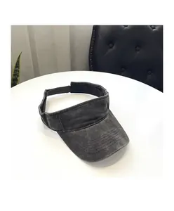 Detail of washed cotton sun visor with wide brim and adjustable buckle strap on white table