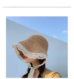 Detailed view of woven straw sun hat with wide white lace trim and long lace ribbon ties