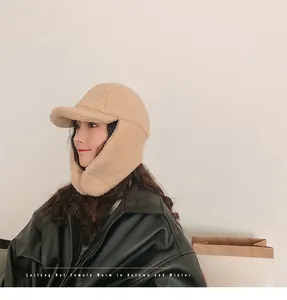 Side view of beige faux shearling trapper hat with soft plush earflaps for winter warmth