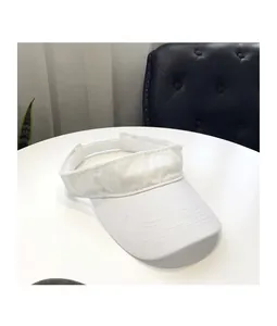 Close-up of white fabric sun visor with adjustable velcro strap on a white table