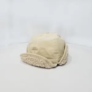 Primer plano del gorro de aviador beige con forro de borreguito blanco y costuras finas