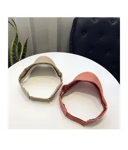 Detail view of khaki and red sun visors with adjustable velcro straps on a table