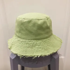 Détail des bords effilochés et texture de toile du chapeau bob de couleur vert clair
