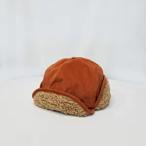 Detalle de gorro de aviador naranja óxido con forro de borreguito y textura de ante