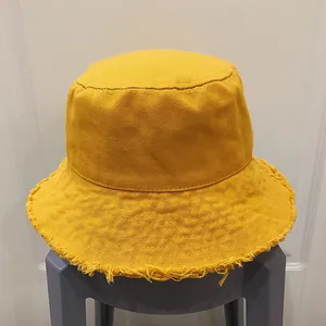 Détail d'un chapeau bob en toile jaune avec bords effilochés pour un look décontracté