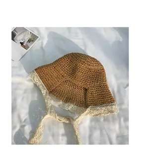 Detailed view of woven straw hat featuring white lace trim and long decorative lace ties