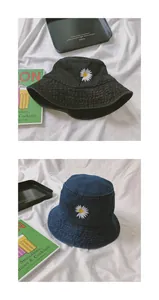 Close-up of white daisy embroidery on black and navy denim bucket hats with fabric detail