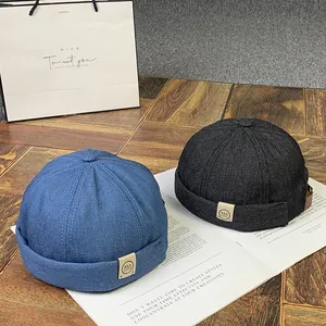 Gros plan sur des bonnets docker en denim avec écussons en cuir sur fond de bois