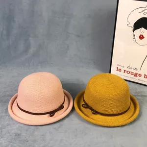 Dettaglio di cappelli cloche in maglia rosa e gialla con fiocco marrone e tesa arrotolata