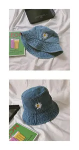 Detail of white daisy embroidery on light blue denim bucket hat with premium cotton texture