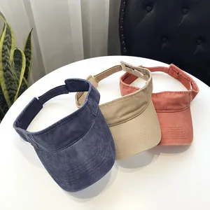 Three retro washed cotton sun visors in blue, khaki, and coral pink on a white table