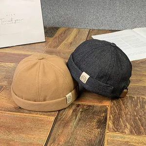 Détail de bonnets docker en denim et camel avec étiquettes sur une table en bois