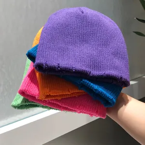 Gorros de punto con bordes desgastados y rotos en colores violeta, azul, naranja y rosa