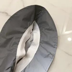 Close-up of reflective grey bucket hat showing elastic strap and durable stitching