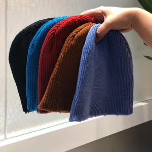 Primer plano de cinco gorros de punto acanalado en colores negro, azul, rojo, púrpura y caramelo
