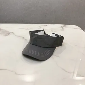 Detail view of a dark grey sun visor hat with three decorative stitching rows and an adjustable strap