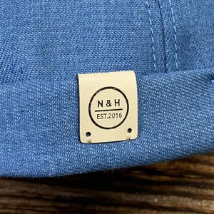 Détail du bonnet docker en denim bleu avec un écusson en cuir au logo N & H embossé