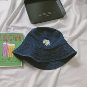 Navy blue denim bucket hat with daisy embroidery on a minimalist white fabric background