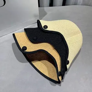 Folded woven straw sun hats in white, black, and yellow with decorative side buttons
