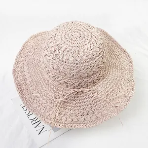 Close-up of hand-woven straw hat with delicate bow detail and wide wavy brim