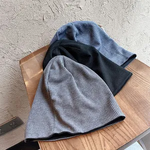 Détail de bonnets en tricot gris, noir et bleu avec une texture en maille gaufrée